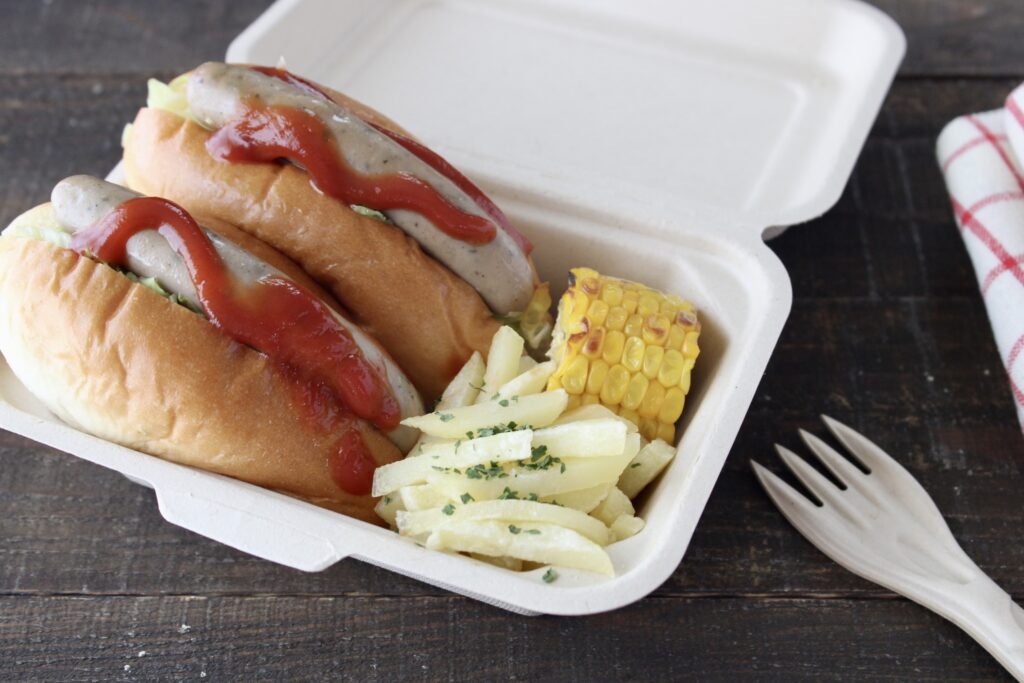 バガス弁当箱に入ったホットドッグとフライドポテトと焼きとうもろこし
