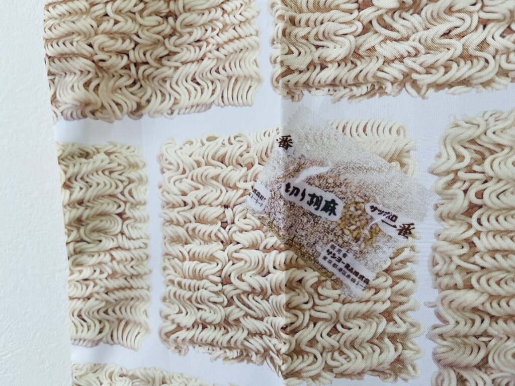 サッポロ一番塩らーめんのパッケージと同じデザインのポーチと麺がプリントされたエコバッグ