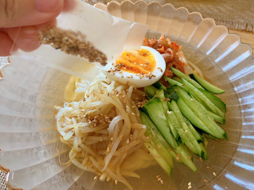 KALDIで買った盛岡発焼肉屋の冷麺、付属の金ゴマを振りかけている様子
