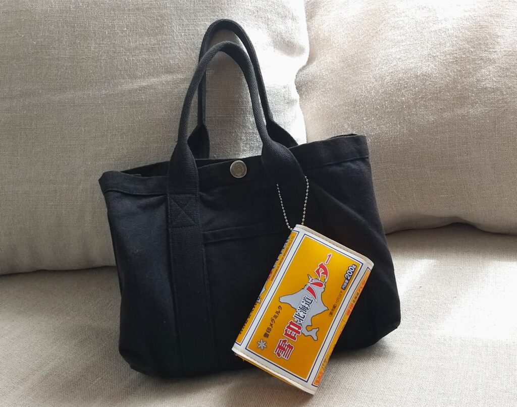 黒いバッグに黄色いポーチがついている