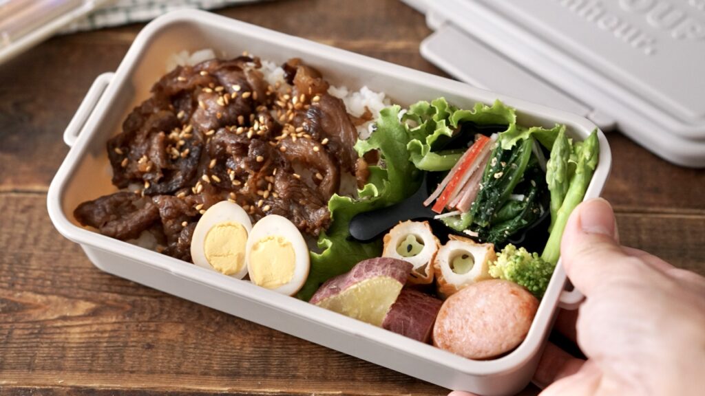 牛肉のしぐれ煮をのせたお弁当。カニカマと小松菜のおひたし、うずらの卵、ちくわ、ブロッコリー、ソーセージ、さつまいもが入った秋らしいお弁当。セリアの１００円のお弁当箱が可愛い。秋色でスモーキーカラー、グレーベージュが素敵。