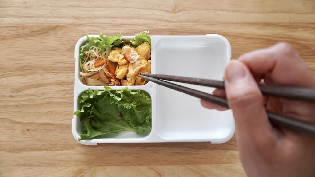 フードマンで作る夫弁当。前日の夜ご飯から、ビーフンを少し残して詰めています。カニカマと卵炒め、鶏の照り焼き、酢蓮根、ソーセージ、筑前煮。